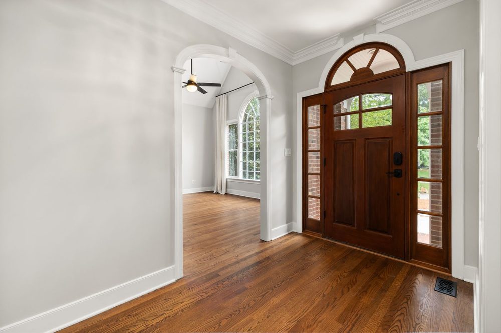 Entry hall with an arched wooden front door, crown moulding, door casing and baseboards