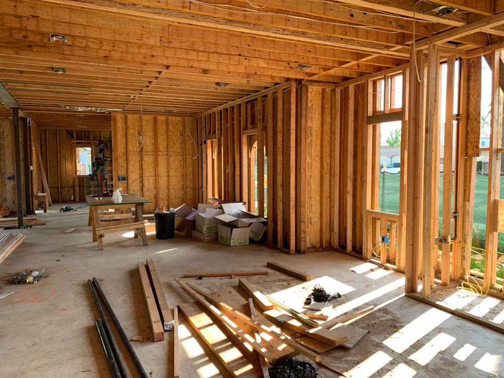 Sunlit interior of a house under construction with wood stud walls and exposed ceiling joists